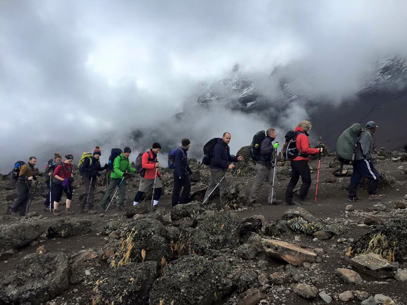 Hikers in single line trekking a mountain in the clouds for both physical and mental benefits