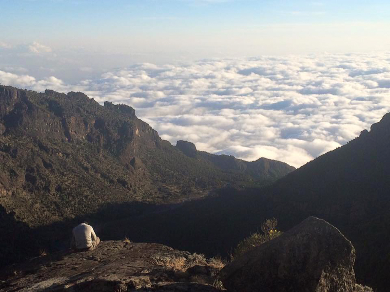 A hiker taking a break above the clouds on a trek
